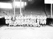 Black-and-white photo of 21 baseball players in two rows; the back row stands while the front row kneels