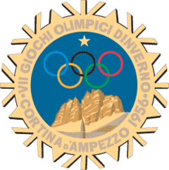 A stylized snowflake with the Olympic rings, a star and mountains. Surrounding the perimeter of the snow flake are the words, "VII Giochi Olimpici Dinverno, Cortina d'Ampezzo 1956"