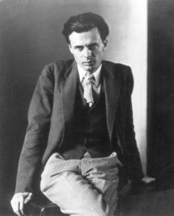 Monochrome portrait of Aldous Huxley sitting on a table, facing slightly downwards.