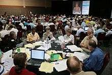 Dozens of people talking at tables in a large room.