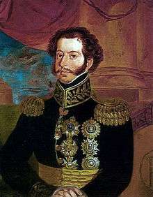 Painted half-length portrait showing a young man with curly hair and mustachios who is wearing an elaborate embroidered military tunic with gold epaulets and medals