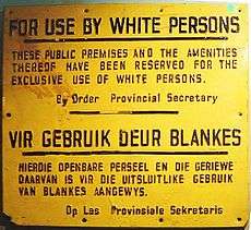 A sign with text in English and Afrikaans. The English text reads: "For Use By White Persons. These public premises and the amenities thereof have been reserved for the exclusive use of white persons. By Order Provincial Secretary".