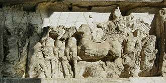 Bas-relief of Roman driver in four-horse chariot, facing left.
