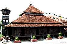 The wooden Kampung Laut mosque with its minaret and an onion-shaped dome on its tiled roof.