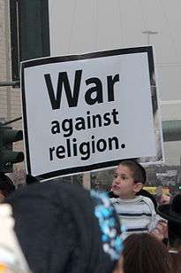 Young boy holding a sign reading, "War against religion"