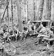 Soldiers resting near makeshift shelter in the jungle