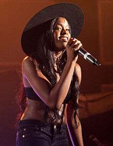 A picture of a woman wearing a black hat and holding a microphone