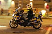 Front view of a yellow BMW R1200RT-P with "Police" signage, police rider and emergency lighting