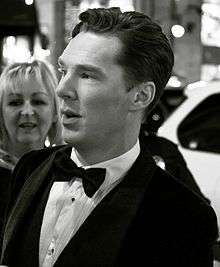 Benedict Cumberbatch in black and white facing left in a tuxedo with brown hair