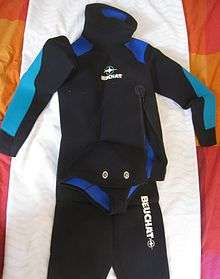 Jacket and trousers of a wetsuit displayed on a cloth, The jacket has a beavertail crotch strap with metal twistlock fasteners.