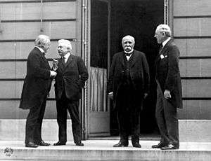 Four men with suits outdoors talking.