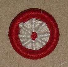 'Blandford Cartwheel' type of Dorset button, made in red and white yarn