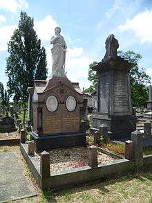 An elaborate funerary monument of red granite, with two white marble tondi of Blondin and his wife, surmounted by a marble statue of a female figure clad in robes holding an anchor