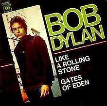 An album cover with a black background. Diagonally aligned, a photo of a man runs across one side of the cover. He is in a brown shirt and looks at the camera, turning the left side of his body towards it. To the right of him are large words printed on the black background, reading: "Bob Dylan", "Like a Rolling Stone", and "Gates of Eden".