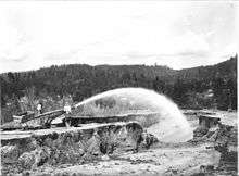 Photo of miners spraying water into a placer