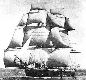 A sailing ship running before the wind, coming toward the observer at an oblique angle, with squaresails and studding sails set on the masts and a headsail set from the bowsprit