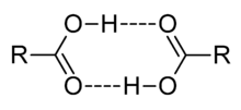 This image illustrates how two carboxylic acids, C O O H, can associate through mutual hydrogen bonds. The hydroxyl portion O H of each molecule forms a hydrogen bond to the carbonyl portion C O of the other.