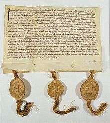 Picture of a deed which has hand-written writing on a yellowed piece of paper with three gold tassles at the bottom
