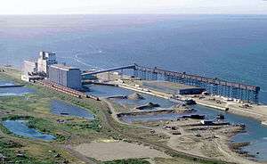 An industrial seaport sits on the coast of a large body of water