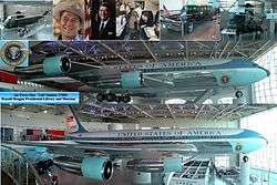 A metal-trussed hanger with a glass front and a shiny floor holds a large jet emblazoned with "United States of American" and other artifacts.