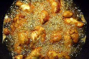 Chicken wings being cooked in a pan filled with corn oil