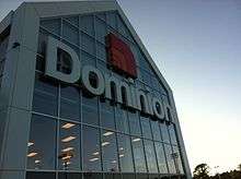 A photograph of the Dominion Store exterior, framed to show the logo.