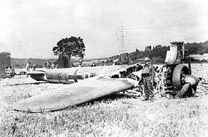 A picture of a twin engine bomber aircraft lying in a field with its front end burnt out.