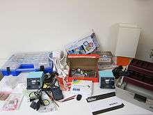 Small electronics tools and supplies arranged on a table against a white wall
