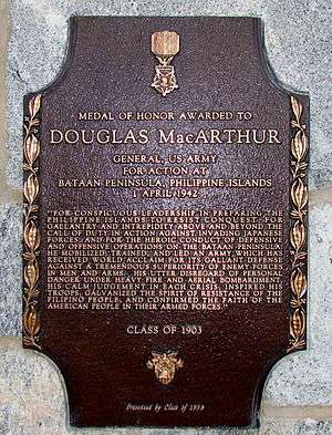 A bronze plaque with an image of the Medal of Honor, inscribed with MacArthur's Medal of Honor citation. It reads: "For conspicuous leadership in preparing the Philippine Islands to resist conquest, for gallantry and intrepidity above and beyond the call of duty in action against invading Japanese forces, and for the heroic conduct of defensive and offensive operations on the Bataan Peninsula. He mobilized, trained, and led an army which has received world acclaim for its gallant defense against a tremendous superiority of enemy forces in men and arms. His utter disregard of personal danger under heavy fire and aerial bombardment, his calm judgment in each crisis, inspired his troops, galvanized the spirit of resistance of the Filipino people, and confirmed the faith of the American people in their Armed Forces."