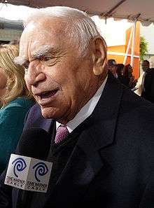 White-haired man with thick eyebrows, wearing tie