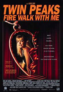 In the center of the poster is half of a golden heart-shaped necklace with a picture of a blonde woman (Laura Palmer) inside it. The necklace is on fire. In the background is red curtains and black-and-white zig-zag flooring.