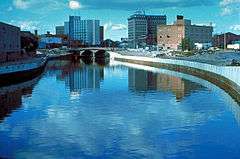 The Flint River in Flint, Michigan, United States, in the late 1970s during a U.S. Army Corps of Engineers flood control project, Taken from approximately halfway between the Grand Traverse Street bridge and Beach-Garland Street bridge, looking east.