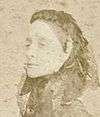 Faded sepia photograph showing the head and shoulders of a lady wearing a veil over her hair