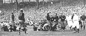 Tackle on the field, in front of a packed grandstand
