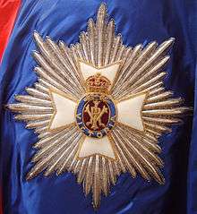 The embroidered star of an English order of Knighthood, with radiating silver rays, topped with a white Maltese cross and royal cypher in the centre