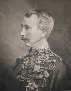 A moustachioed man with closely cropped hair and a chest covered in military medals