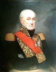 Color painting of a grim-faced older man with a receding hairline. The man, whose arms are crossed, wears a dark blue military uniform with gold epaulettes, gold braid, and a red sash across his chest.