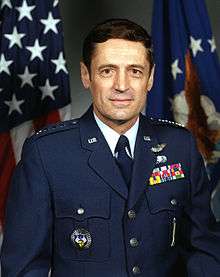 man in Air Force uniform, American flag in background