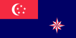 A red rectangle at the top left corner of the flag, charged with a white crescent and five white stars arranged in a pentagon. The rest of the flag is coloured blue. At the bottom right part of the flag is an eight pointed star that is alternating red and white.