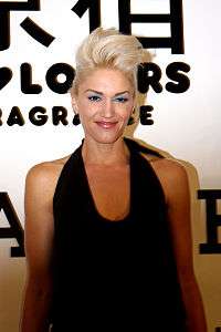 A light-skinned blonde-haired woman is dressed in a black sleeveless shirt.