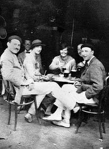 photograph of three men and two women sitting at a sidewalk table