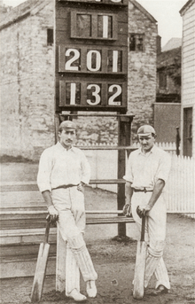 A black and white picture of Lionel Palairet and Herbie Hewett stood in front of a scoreboard reading 1, 201, 132.