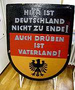 Black, red and gold West German sign reading "Hier ist Deutschland nicht zu Ende. Auch drüben ist Vaterland!"