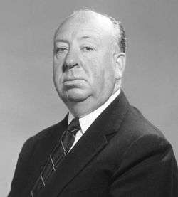 Black and white image shows head and shoulders shot of a man dressed in suit and tie.