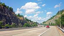 A six lane freeway running through rock cuts in a mountain