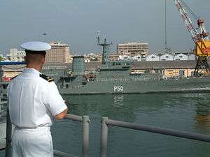 Naval officer looking at a long, grey ship