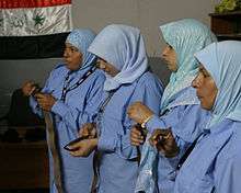 Four young women in blue hijabs, holding brown belts