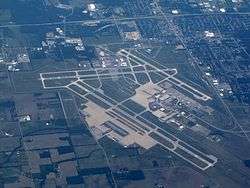 Aerial image of Dayton International Airport showing runways, taxiways, buildings, and surrounding area.