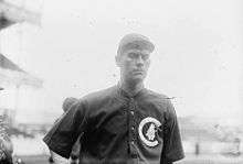 A man in a baseball uniform is shown from the waist up.