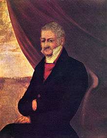 Painted half-length portrait depicting a gray-haired man with a thin face dressed in a plain black coat over a red vest and high-collared white shirt and sitting in front of a half-opened drape revealing an avenue with a building in the distance